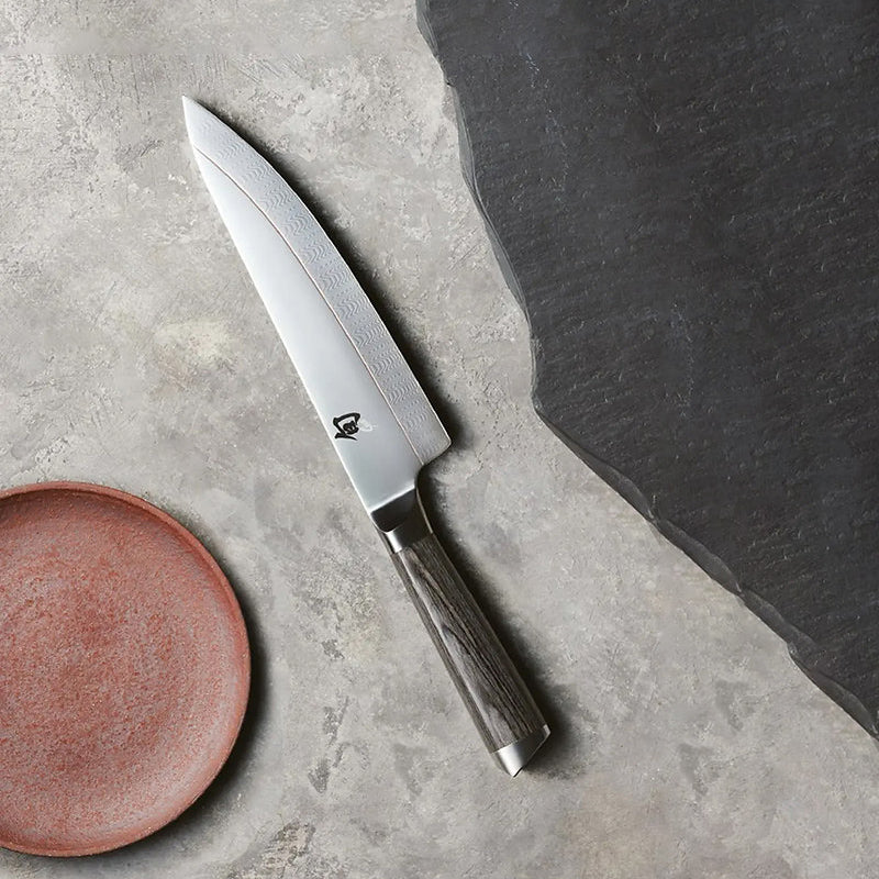 Santoku von KAI - Serie: Shun Kagerou,
mit gerader Schneide und nach unten gezogenem Klingenrücken, handgefertigt, beidseitig geschliffen, 
Griff: Pakkaholz, grau-meliert
Online-Shop Home-and-Kitchen.de