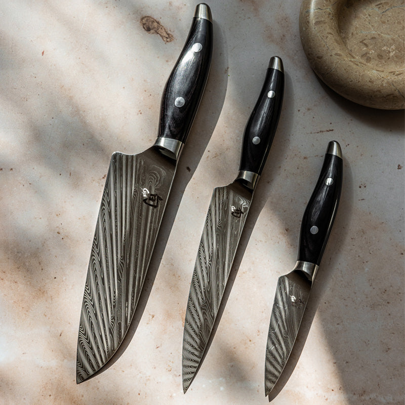 Strahlenförmiges Damastmuster auf den Klingen der Messer aus der KAI - Serie Shun Nagare Black
Online-Shop Home-and-Kitchen.de