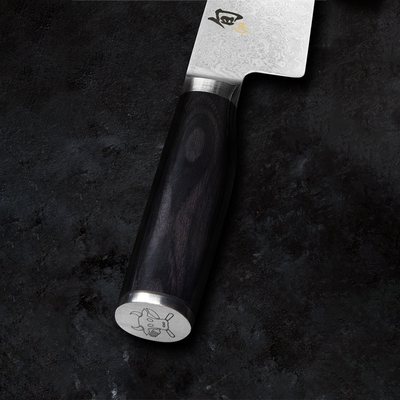 Griff aus schwarzem Pakkaholz und  Bullenkopf-Logo von Tim Mälzer Santoku-Messer  von KAI - Serie: Shun Premier Tim Mälzer MINAMO
Online-Shop Home-and-Kitchen.de