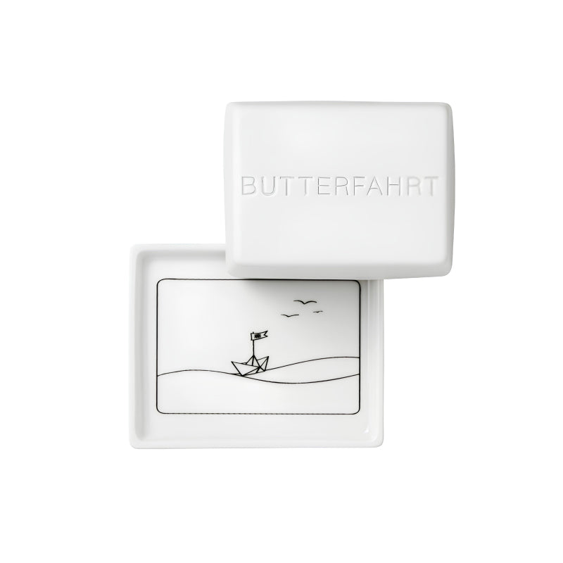 Kleine Butterdose BUTTERFAHRT, Porzellan  für 125 gr Butter, Deckel mit Prägeschrift, Bodenplatte mit schwarzer Zeichnung mit Wellen, Vögeln und Boot.
von Räder Design