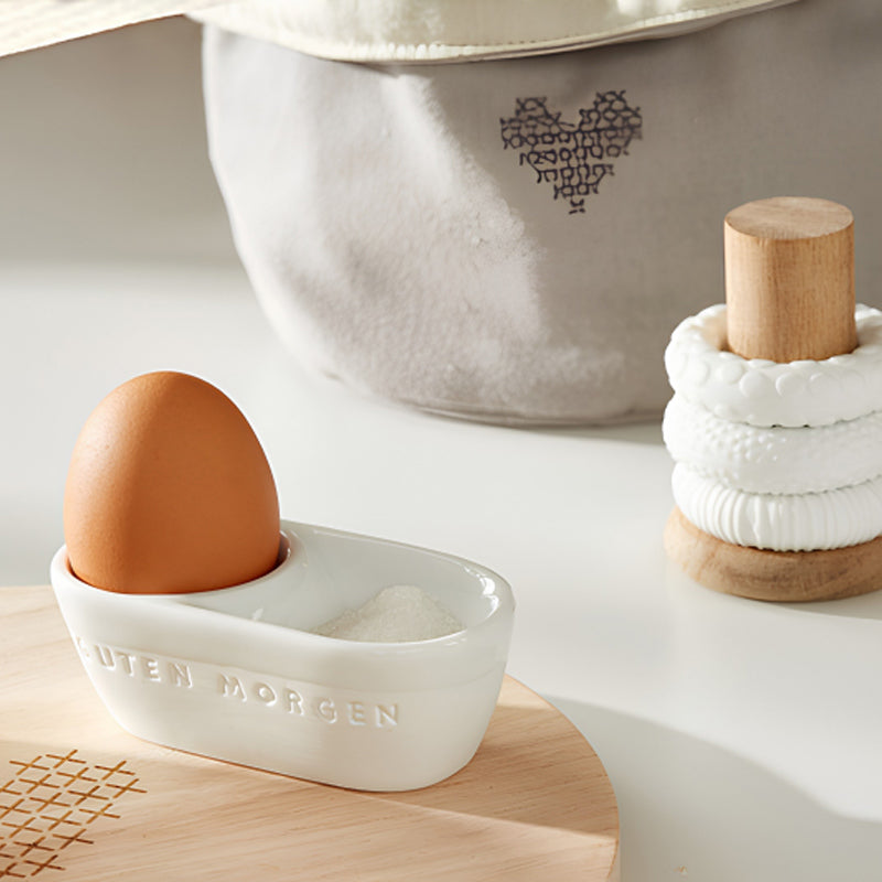 Keine Eierschalen auf dem Teller, nichts stört beim Essen des Frühstückseies. Der GUTEN MORGEN-Porzellan-Eierbecher passt auf jeden Frühstückstisch. Praktisch dabei ist die zusätzlich integrierte kleine Mulde für Salz oder die Eierschalen. Eine Prägung auf der Außenseite wertet den schicken Eierbecher erst richtig auf. Seine Größe beträgt 9,5x5x3,5 cm.
