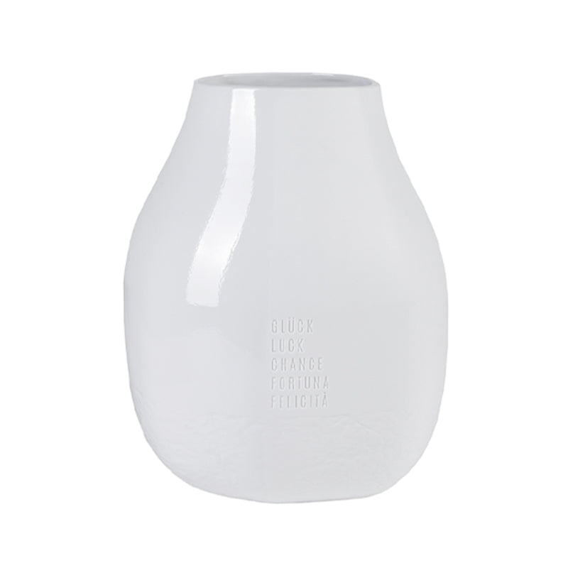 Die weiße Porzellan-Blumenvase auf auf ihrer Außenseite in Prägeschrift in 5 Sprachen das Wort "Glück" stehen. Sie hat eine Größe von 20x19x25 cm und ist für Frische- und Trockenblumen gleichermaßen geeignet. Sie ist von Räder Design und erhältlich im Online Shop Home-and-Kitchen.de
