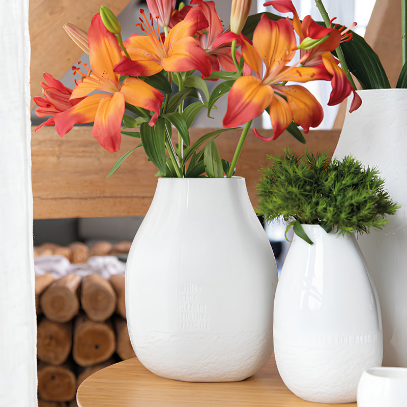 Besonders fallen Blumen mit kräftigen Farben in der weißen Porzellan-Blumenvase auf, die auf ihrer Außenseite in Prägeschrift in 5 Sprachen das Wort "Glück" stehen hat. Sie hat eine Größe von 20x19x25 cm und ist für Frische- und Trockenblumen gleichermaßen geeignet. Sie ist von Räder Design und erhältlich im Online Shop Home-and-Kitchen.de