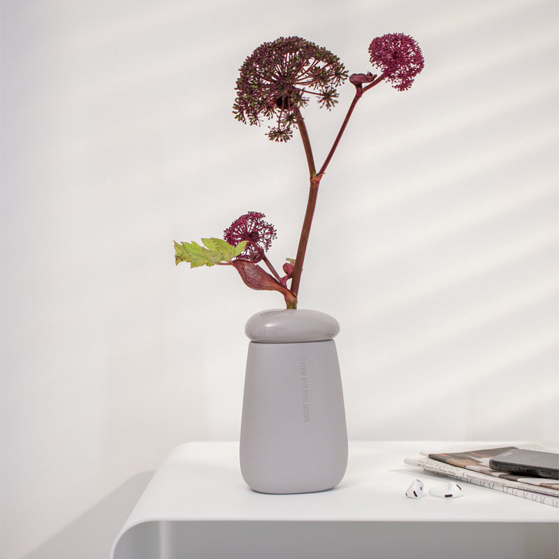 Besonders schön sieht die von Räder Design Steingut-Vase "Wachse über dich hinaus", mit einzelnen Blumenstielen aus. Sie wurde in Kieselstein-Form gestaltet und auf der matten Außenseite mit einem Schriftzug versehen. Ihr Inneres ist glasiert. Ihre Größe beträgt 10,3x8,4x17,4 cm.